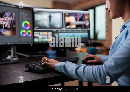 Gros plan d'un vidéaste professionnel assis à son bureau tout en améliorant les séquences vidéo à l'aide d'un logiciel spécialisé. Éditeur de film de la société créative expert assis sur un poste de travail multi-moniteur. Banque D'Images