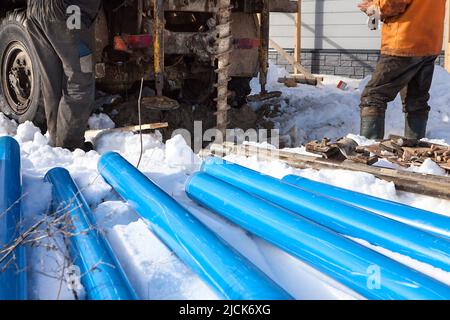 Travaux de construction de puits d'eau, tuyaux en plastique bleu sur le sol enneigé Banque D'Images