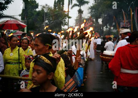 Femme plus âgée portant une torche traditionnelle pour une série d'événements célébrant le jour de Nyepi à Kediri, Eastjava, Indonésie Banque D'Images