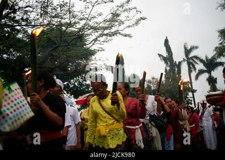 Femme plus âgée portant une torche traditionnelle pour une série d'événements célébrant le jour de Nyepi à Kediri, Eastjava, Indonésie Banque D'Images