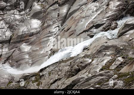 Source du Rhône, l'eau brute tombe entre les rochers de montagne. Haute alpes paysage de terrain aride avec chute d'eau. Banque D'Images