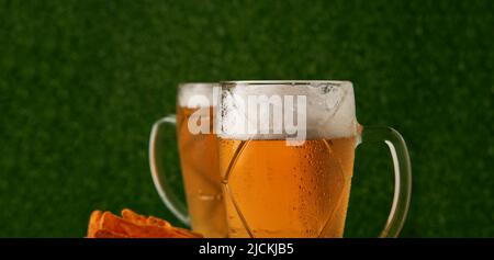 Deux verres de bière avec ballon de football sur fond d'herbe verte. Concept de fan de football Banque D'Images