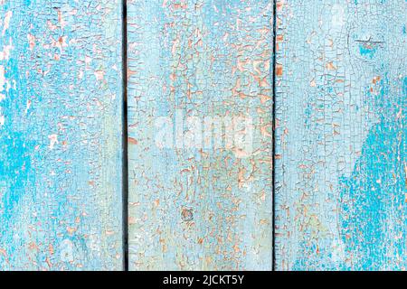 Surface texturée d'une planche en bois avec une couche écaillée et craquelée de peinture bleu clair et rouge. Anciennes planches en bois peint, vieux matériaux de mur naturel Banque D'Images