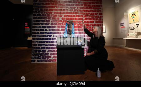 Brighton, Royaume-Uni. 14th juin 2022. Helen Grundy, responsable des expositions, polit le cabinet contenant le Barclays FA Women's Super League Trophée qui fait partie de l'exposition de football des femmes Goal Power au musée et galerie d'art de Brighton. Credit: James Boardman / Alamy Live News Banque D'Images