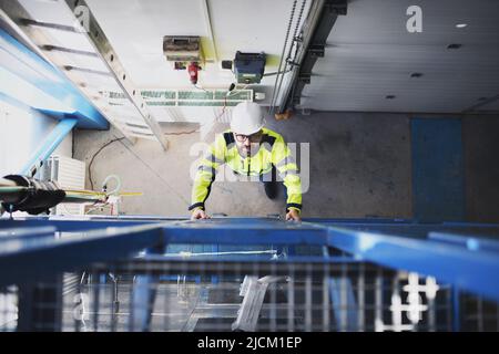 Vue de dessus d'un ingénieur de l'usine industrielle qui monte sur l'échelle. Banque D'Images