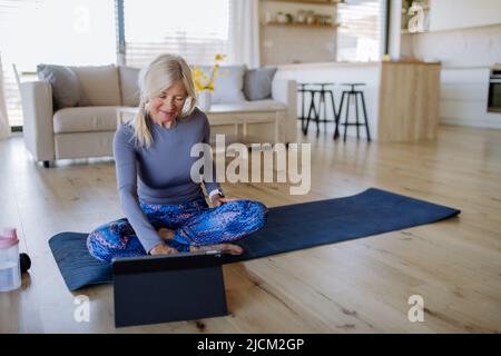 FIT femme senior ayant cours d'exercice en ligne à la maison, concept de style de vie actif. Banque D'Images