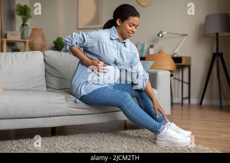 Femmes enceintes Black Lady laçage Chaussures touchant le ventre ayant le spasme intérieur Banque D'Images