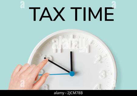La main d'une femme déplace la flèche sur l'horloge, gros plan. Heure de taxe. Le concept de paiement des impôts et des délais. Banque D'Images