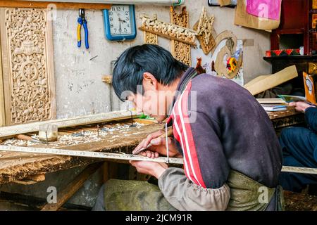 Un jeune tibétain sculptant des motifs complexes sur du bois à Lhassa, au Tibet. Banque D'Images