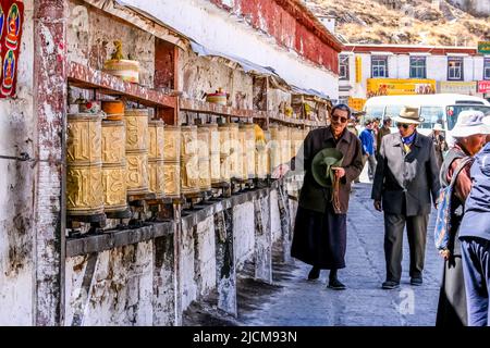 Tibétains tournant les roues de la prière avant d'entrer dans le Palais du Potala à Lhassa, au Tibet. Banque D'Images