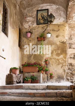 Amelia (Italie) allée médiévale, avec fleurs et image de la Vierge et de l'enfant, illuminée par un lampadaire Banque D'Images