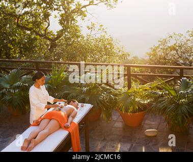 Femme recevant un massage tibétain au coucher du soleil, Ananda Spa, Ananda dans l'Himalaya, le Palace Estate, Narendra Nagar, Tehri Garhwal, Uttarakhand, Inde. Banque D'Images