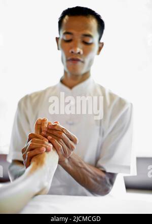 Un thérapeute balinais de sexe masculin propose un massage de réflexologie des pieds au spa Ayung, dans les jardins suspendus d'Ubud, à Bali, en Indonésie. Banque D'Images