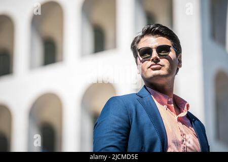 Homme d'affaires avec lunettes de soleil. Veste et chemise bleu. En arrière-plan un bâtiment. Banque D'Images