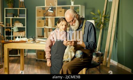 Un grand-père de Caring enseigne à sa petite-fille adolescente à coudre dans un atelier à domicile. Artisanat, Hobby. Communication des générations, Happy Family Time Banque D'Images