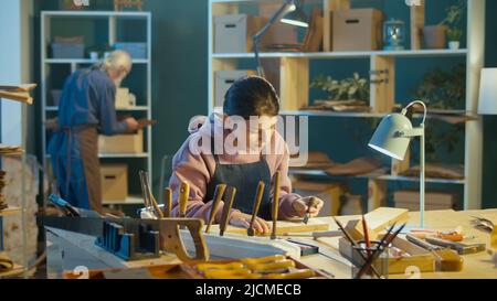 Grand-père attentionné avec sa petite-fille adolescente passer du temps ensemble, travailler sur le bois, profiter de la communication dans l'atelier. Garage passe-temps. Communicati Banque D'Images