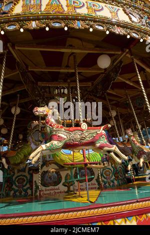 Les chevaux circulaires traditionnels du champ de foire se miguent dans des couleurs vives au soleil du Royal Cornwall Show. Toujours une attraction de tous les âges Banque D'Images