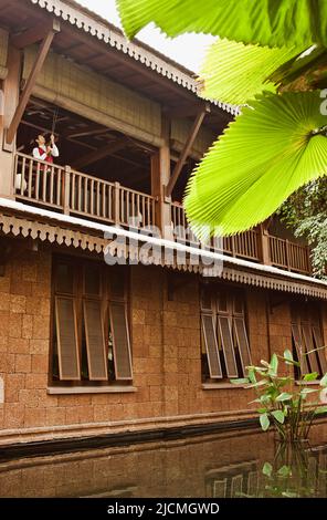 Un membre du personnel de l'hôtel dessine les stores du salon du deuxième étage pour laisser entrer la lumière du matin dans un hôtel, Siem Reap, Cambodge. Banque D'Images