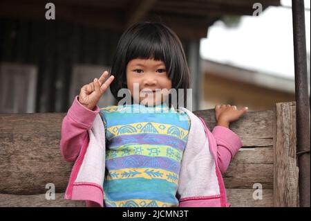 Province de montagne, Philippines: Jeune Sagada local, une fille avec les yeux asiatiques mignons et droit en travers des bangs, tenant un signe de paix à la caméra. Banque D'Images