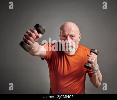 homme âgé (fin 60s) s'exerçant avec des haltères, senior actif et concept de forme physique Banque D'Images