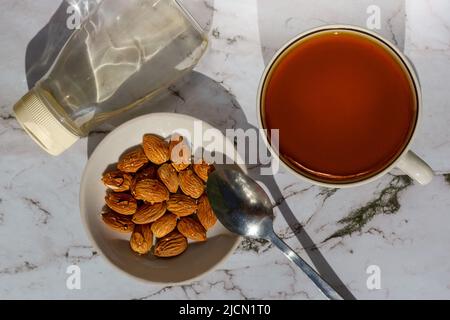 Sirop d'amande biologique fait maison dans une bouteille et noix versées. Succédanés de sucre. Banque D'Images