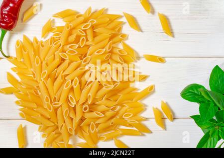 Pâtes penne, vert basilic, parmesan, le sésame, l'Ail, piment, les œufs se trouvent sur un arbre blanc tableau Banque D'Images