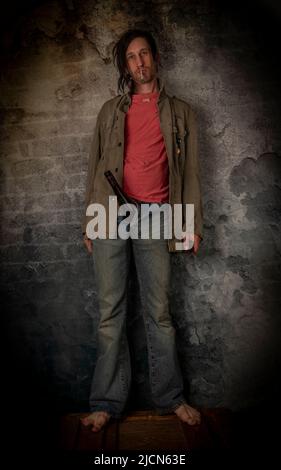 Junkie homme avec cheveux noirs et bouteille avec joint près de vieux mur de pierre Banque D'Images