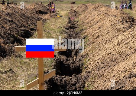 De nouvelles tombes fraîchement creusées et une croix en bois avec le drapeau de la Russie, un cimetière pour une tombe de masse de soldats russes, la guerre en Ukraine Banque D'Images