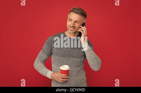 concept de communication. souriant grizzled gars parlant au téléphone sur fond rouge. Banque D'Images