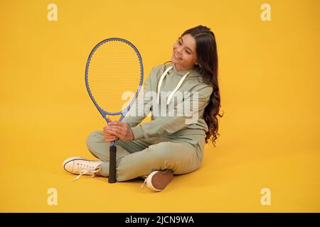 une jeune fille gaie dans des vêtements de sport tient des raquettes de tennis sur fond jaune, sport Banque D'Images