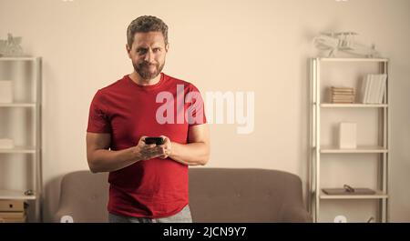 un homme souriant en tshirt rouge discutant sur un téléphone mobile, faisant des coups de pieds en ligne Banque D'Images