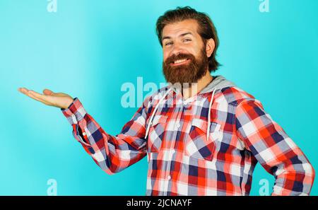 Un homme souriant présente ou montre quelque chose à portée de main avec un espace de copie pour le produit. Remise. Vente. Banque D'Images