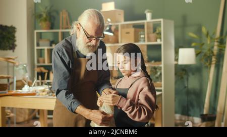 Un grand-père de Caring enseigne à sa petite-fille adolescente à coudre dans Workshop Banque D'Images