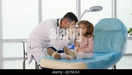 Un médecin traitant examine l'oreille d'une petite fille à l'aide d'un dispositif spécial. Banque D'Images