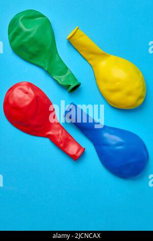 Les ballons multicolores non gonflés sont rouge, jaune, bleu et vert en diagonale sur un fond bleu. Vue de dessus avec espace de copie Flat lay Banque D'Images