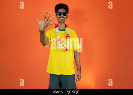 Homme dans une tenue de football jaune célébrant l'isolé sur fond orange. Banque D'Images