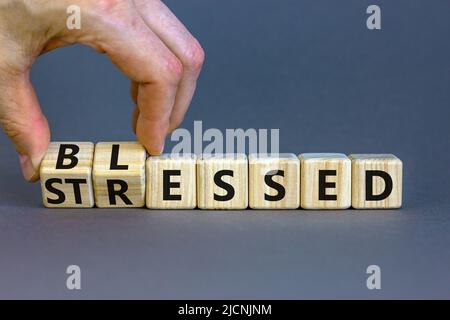 Symbole béni ou stressé. L'homme d'affaires tourne des cubes en bois et change le mot concept souligné à Blessed. Magnifique fond gris de table. Bus Banque D'Images