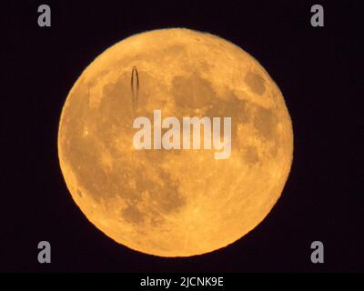 Sheerness, Kent, Royaume-Uni. 14th juin 2022. Météo au Royaume-Uni : un jet de haute altitude est vu pour laisser un sentier de vapeur en passant devant la Super Strawbery Moon au-dessus de Sheerness, Kent ce soir. Crédit : James Bell/Alay Live News Banque D'Images