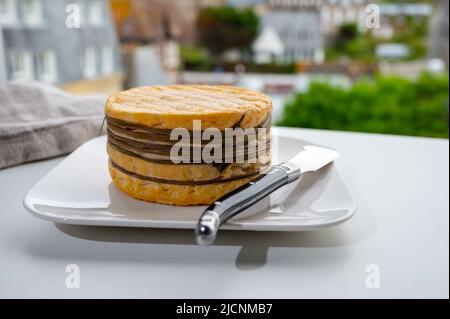 Dégustation de fromage de vache livarot jaune de Lisieux, région du Calvados et vue sur les maisons anciennes d'Etretat, Normandie, France Banque D'Images