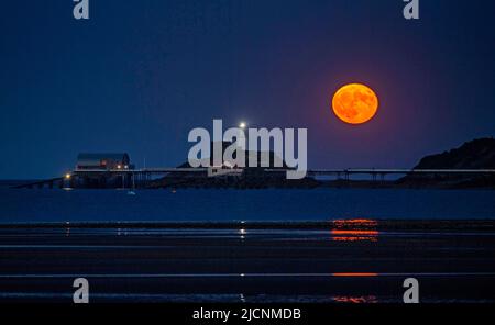 Swansea, Royaume-Uni. 14th juin 2022. Une pleine lune de Strawberry s'élève ce soir au-dessus du phare et de la jetée dans le village de Mumbles près de Swansea. Credit: Phil Rees/Alamy Live News Banque D'Images