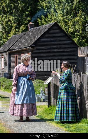 Deux femmes parlant portant des vêtements traditionnels du 1850s au fort Nisqually Living History Museum à Tacoma, Washington Banque D'Images