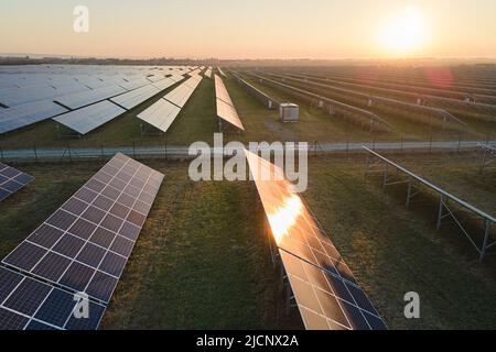 Vue aérienne de la grande centrale électrique durable avec de nombreuses rangées de panneaux photovoltaïques solaires pour produire de l'énergie électrique propre au coucher du soleil Banque D'Images