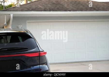 Véhicule stationné devant un grand garage double porte sur une allée pavée d'une maison américaine contemporaine typique Banque D'Images