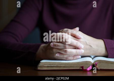 Les mains de la femme dans la posture de la prière au-dessus de la bible ouverte. Copier l'espace. Banque D'Images