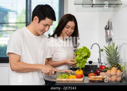 un jeune couple coupe des légumes pour préparer des aliments sains dans la cuisine à la maison Banque D'Images