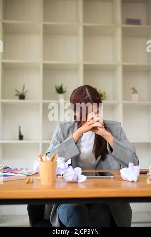 Portrait d'une jeune femme d'affaires asiatique se sentant bouleversée, n'a pas manqué de passion et triste avec son travail, assis à son bureau. Banque D'Images