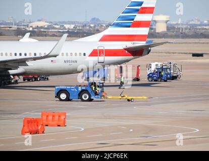 Un avion d'American Airlines desservi par des agents de service de rampe à l'extérieur d'un terminal à l'aéroport DFW (aéroport de Dallas-fort Worth) Banque D'Images