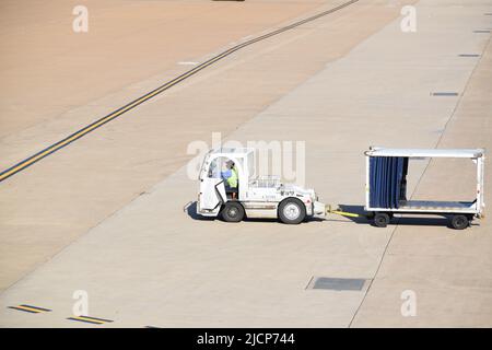 Un employé du service de rampe United Airlines conduit un tracteur et tire une trémie à bagages vide à l'aéroport international de Dallas fort Worth (aéroport DFW) Banque D'Images