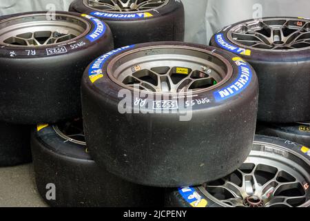 Pneus de course lisses Michelin Pilot Sport GT usagés montés sur jante, empilés à l'arrière du paddock. Banque D'Images