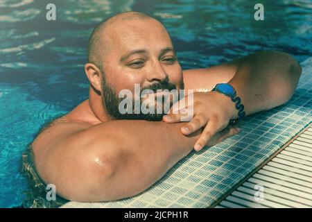 Portrait de taille plus grand homme souriant heureux se relaxant dans la piscine. Banque D'Images